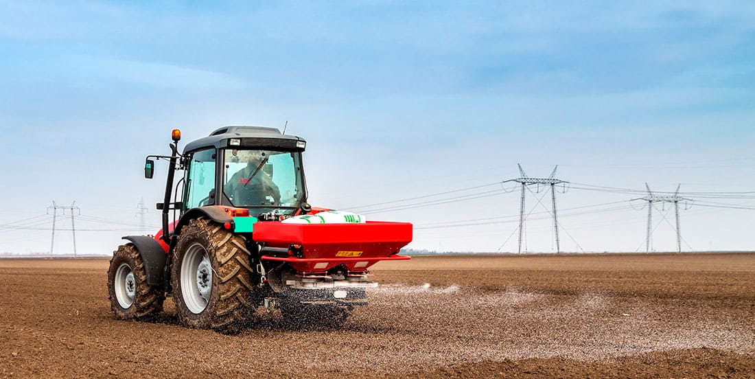 Maquinário agrícola jogando algum adubo NPK na plantação, da mesma forma que ele faz com diversos tipos de NPK.